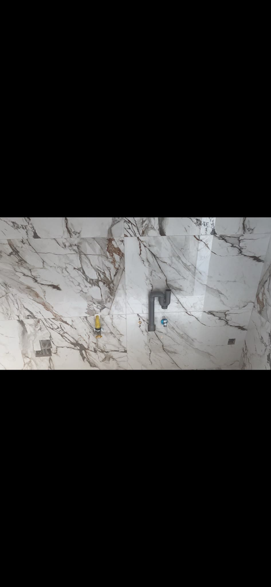 WC suspendu et lave-mains sur carrelage marbre blanc et or
