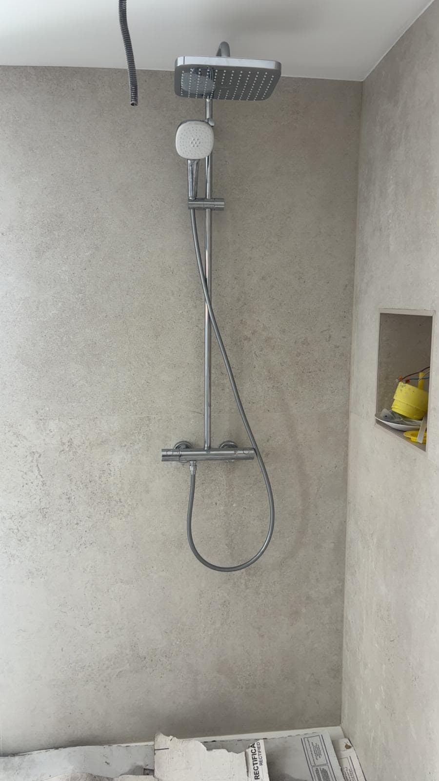 Douche italienne avec carrelage effet béton gris et colonne de douche chromée